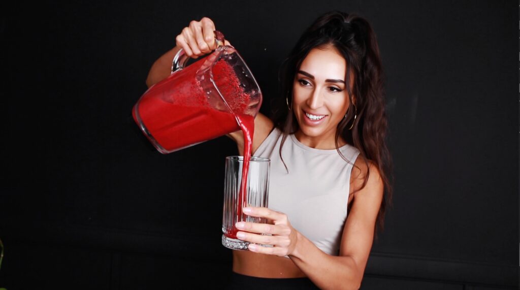 female pouring vegan protein shake from blender